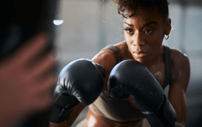 fitness-fighting Eine Frau hat schwarze Boxhandschuhe an und ist beim Boxtraining