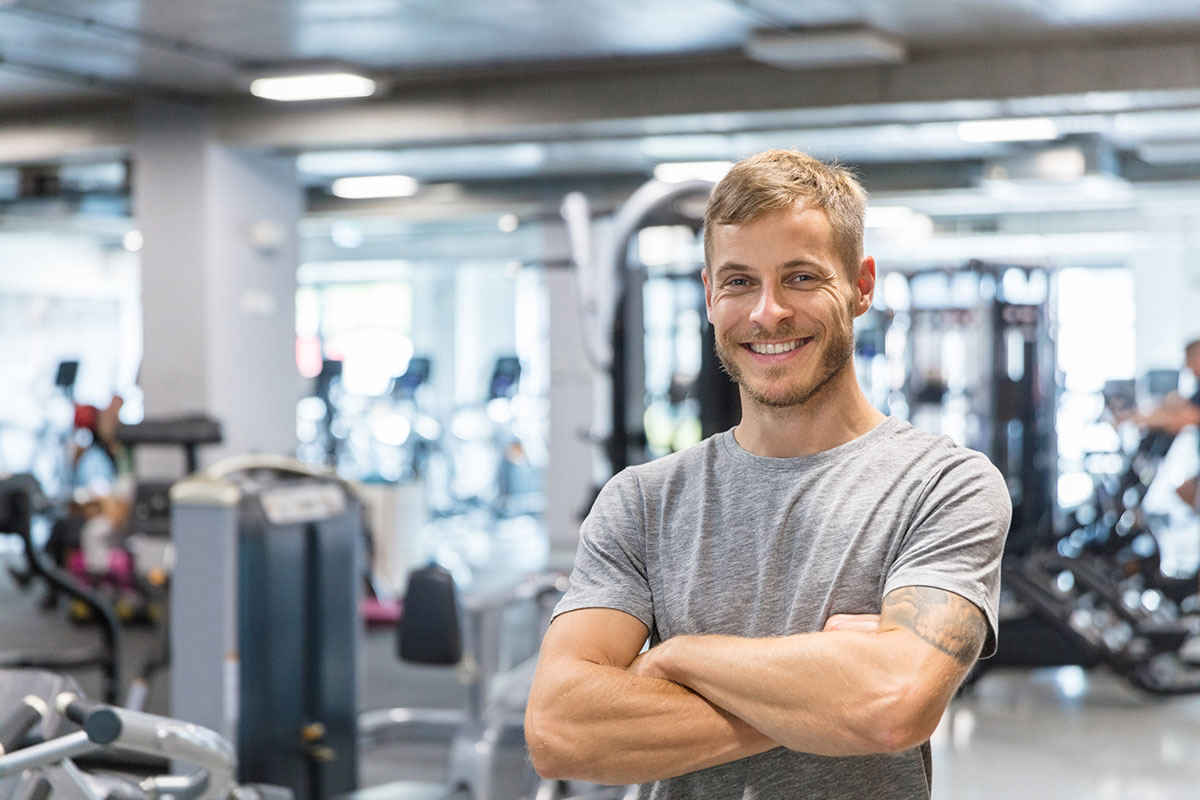 Ein Mann steht lächelnd im Fitnessstudio