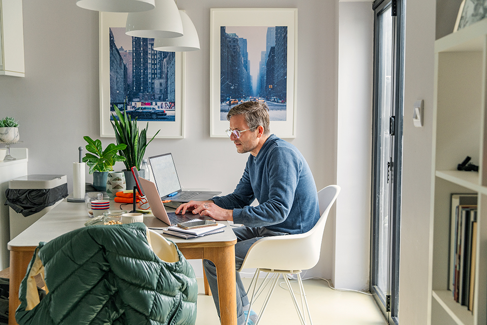 Seitenansicht eines Mannes, der von zu Hause aus am Esstisch arbeitet Ein mann macht homeoffice vom Esstisch aus.