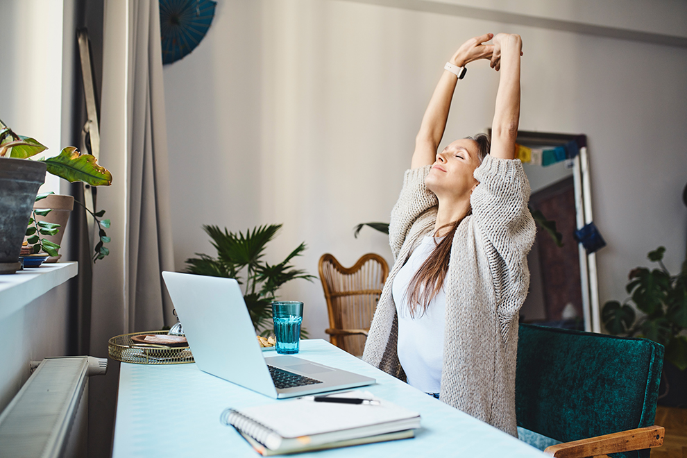 Frau im Homeoffice Eine Frau im Homeoffice die sich am Schreibtisch streckt.