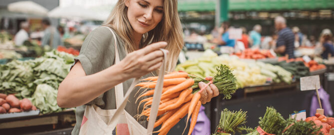 Frau kauft auf einem Markt Gemüse ein