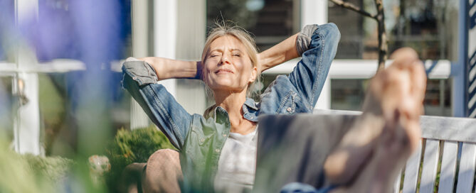 Frau sitzt im Garten und sonnt sich