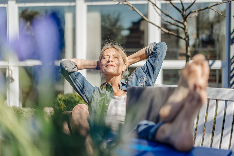 Frau sitzt im Garten und sonnt sich