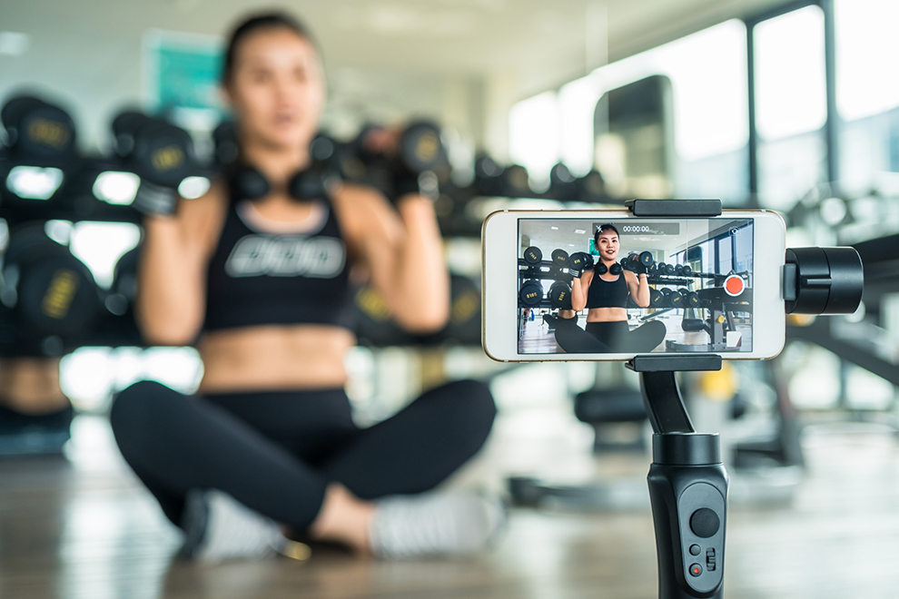 Frau macht ein Trainingsvideo Frau erklärt online Fitness mit einem Smartphone.