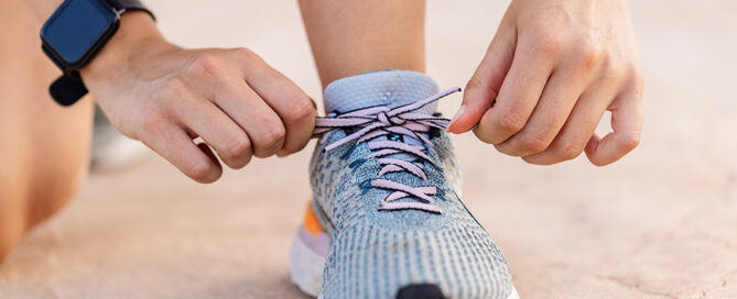 Person bindet sich den Laufschuh zu