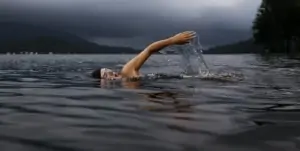 Person schwimmt im See Person schwimmt im See bei Dämmerung