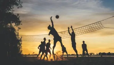 Volleyball Gruppe spielt Volleyball im Sonnenuntergang
