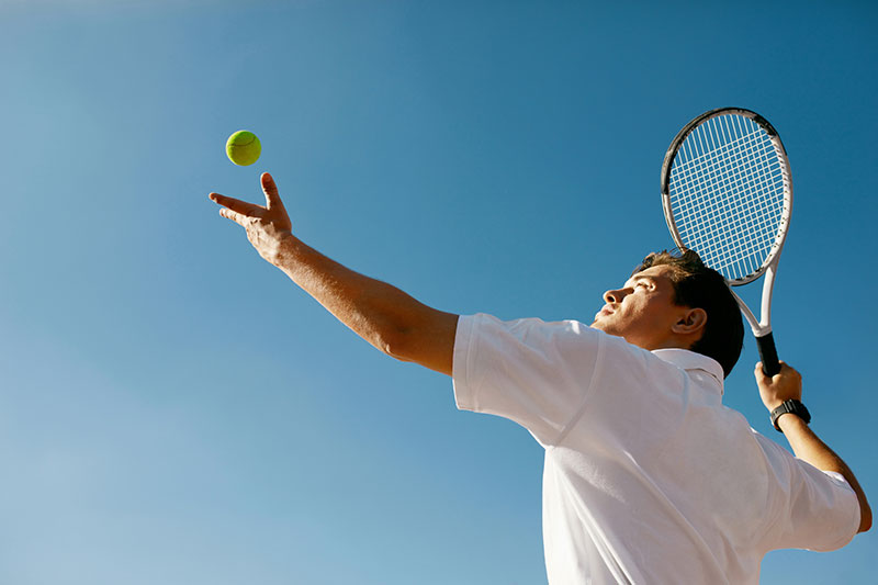 hansefit_firmenfitness_sportarten Ein Mann macht den Aufschlag beim Tennis