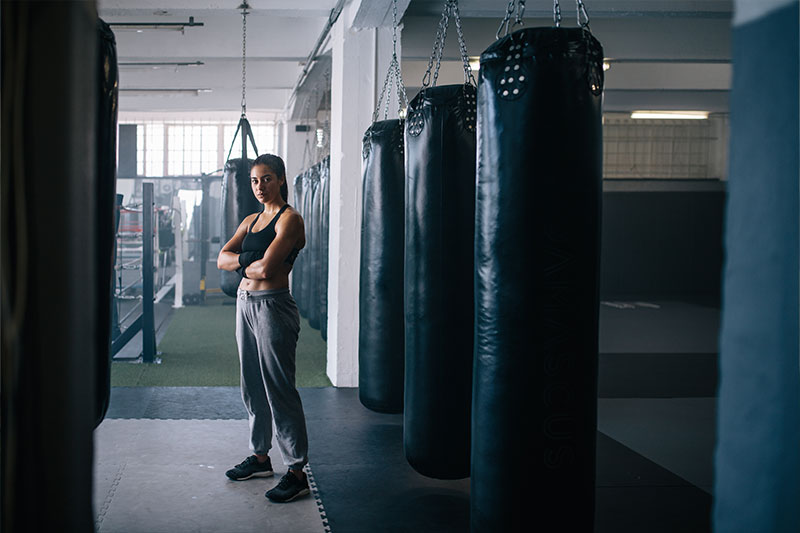 hansefit_firmenfitness_sportarten_06 Eine Frau steht im Fitnessstudio bei den Boxsäcken.