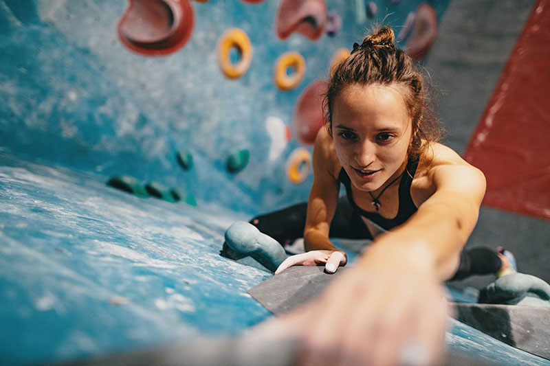 hansefit_partner_anfrage_02 Eine Frau erklimmt eine Wand beim bouldern