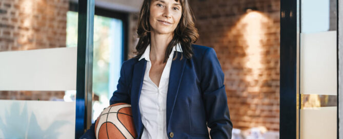 Eine Frau in einem Business-Outfit, die einen Basketball hält.