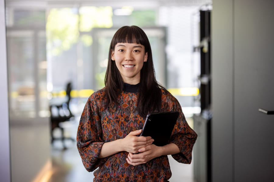 employer-branding-massnahmen2 Eine Frau hat Dokumente in der Hand und lächelt.