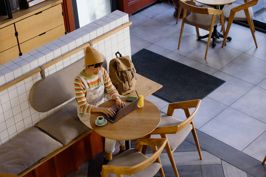 hybrides-arbeiten-header Hybrides Arbeiten: Eine Frau arbeitet an ihrem Laptop in einem Cafe
