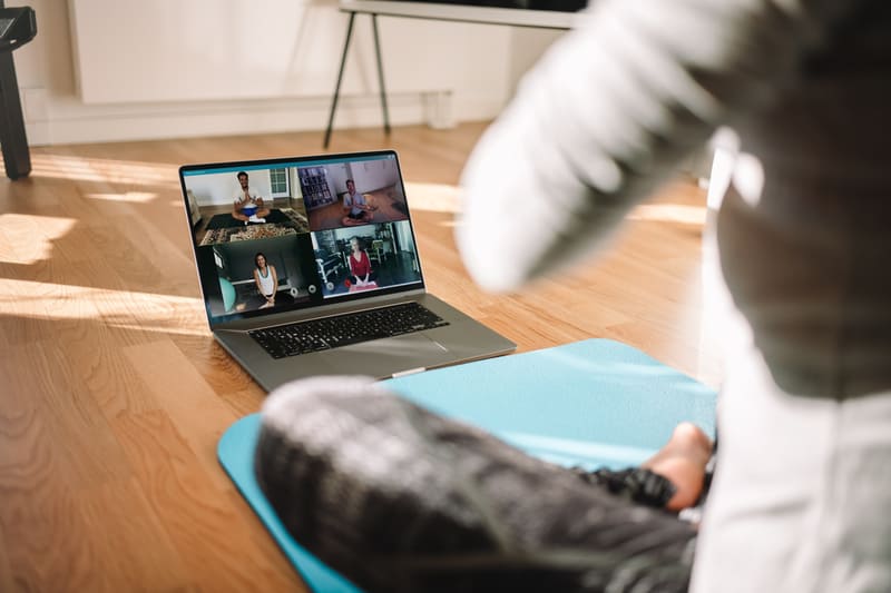 teambuilding-massnahmen-artkebild Eine Frau sitzt auf einer Yogamatte vor dem Laptop.