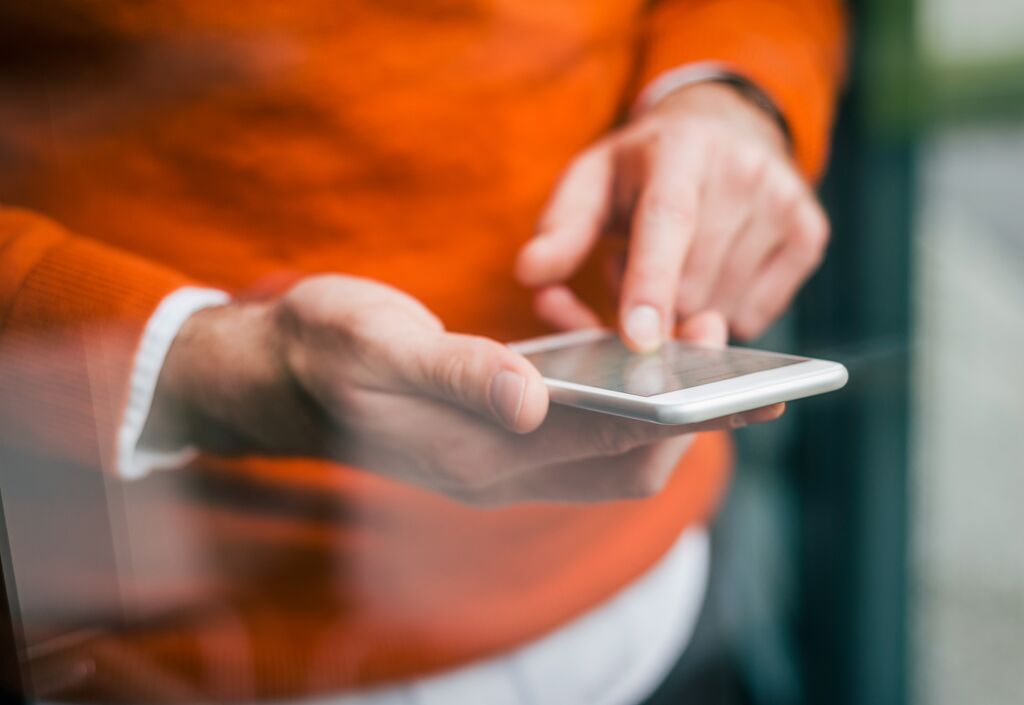 gutscheine-sachbezug-regeln Mann scrollt auf dem Handy durch seine Gutscheine aus dem Sachbezug und studiert die Regeln.