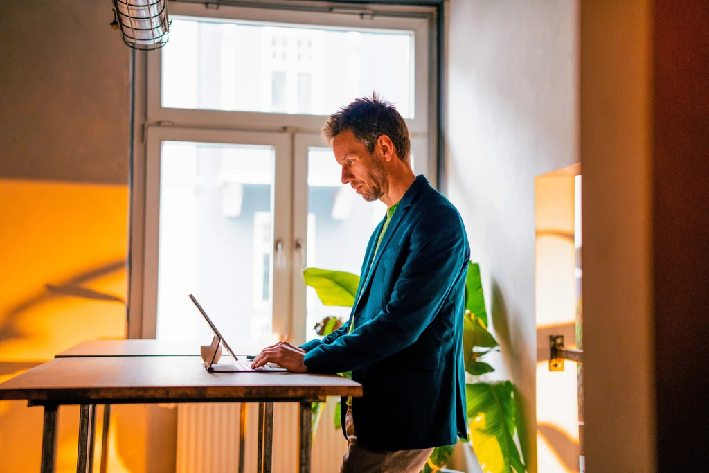 laptop-buero-work-standingatdesk Mann arbeitet an einem Stehschreibtisch am Laptop
