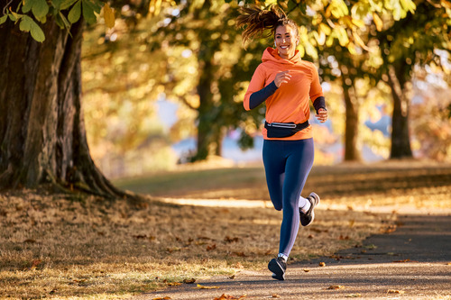 laeuferin-park-herbst-joggen Eine Frau läuft durch einen herbstlichen Wald.