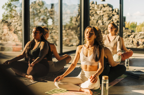 yoga-gruppe-meditation-studio Eine Gruppe sitzt in einem Yoga Studio und meditiert.